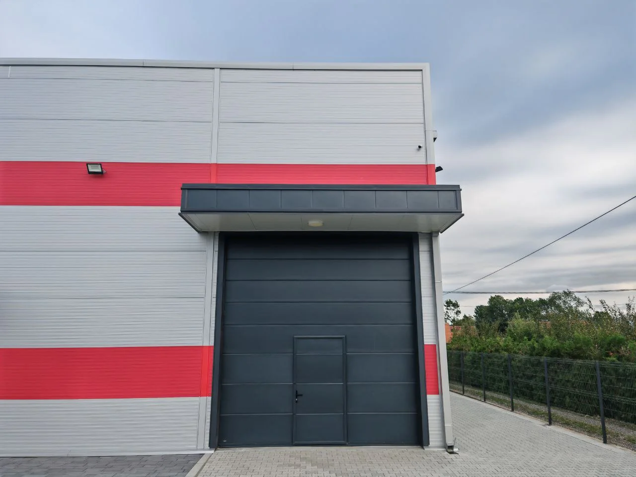 Industrijska vrata sa nadstrešnicom na crveno-beloj fasadi