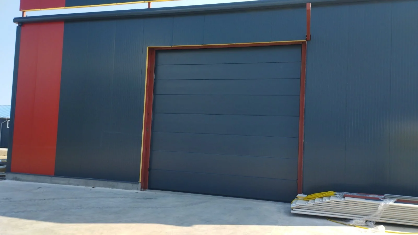 Industrijska segmentna garažna vrata na hali sa crveno-žutom fasadom